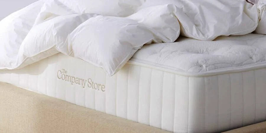 The Company Store luxury mattress showcased, highlighting its hand-tufted wool rosettes and silk, wool, and cashmere quilted top.
